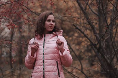 Girl looking away while standing on tree