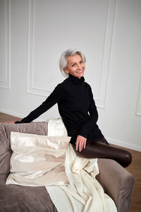 Stylish mature woman on sofa in living room