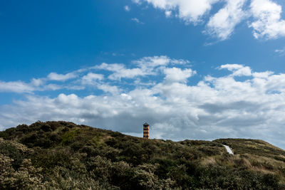 Low angle view of lighthouse by building against sky