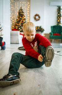 Full length of boy sitting on bed at home