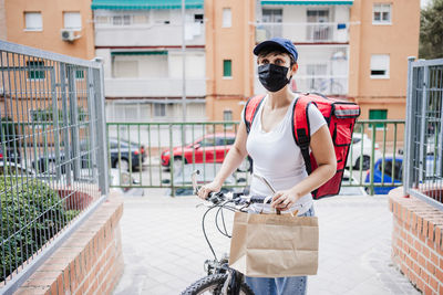 Delivery person wearing mask standing against building