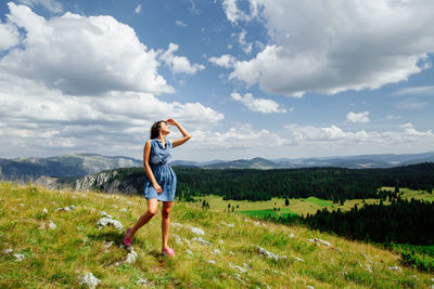 Full length of woman with arms raised against sky