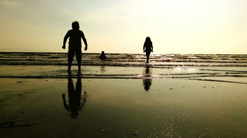 Silhouette people on beach against clear sky