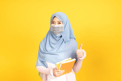 Portrait of mid adult man standing against yellow background