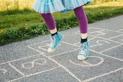 Closeup of chld girl playing jumping hopscotch outdoor. funny activity game for kids on playground 