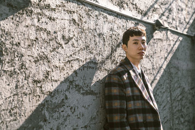 Portrait of young man standing against wall