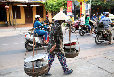 Full length of vendor with containers walking on city street