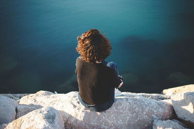 Woman sitting on rock over sea