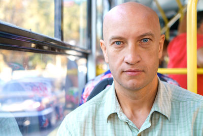 Bald caucasian man rides in public transport while sitting by the window