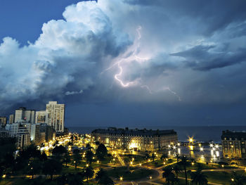 Lightning over city buildings against storm clouds