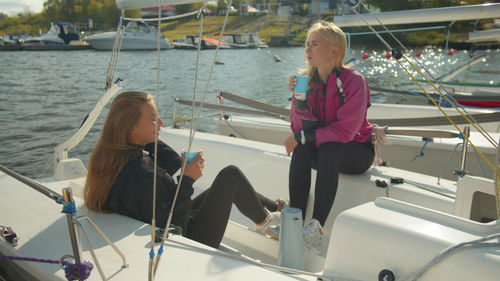 Girls sitting on yacht while holding coffee cup