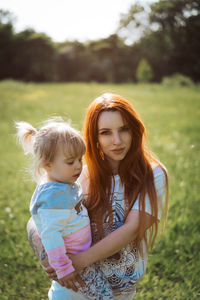 Portrait of mother carrying daughter at park