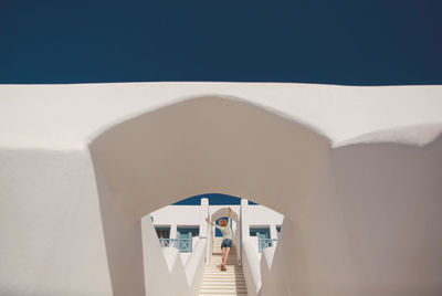 Low angle view of young woman with arms raised while climbing building steps