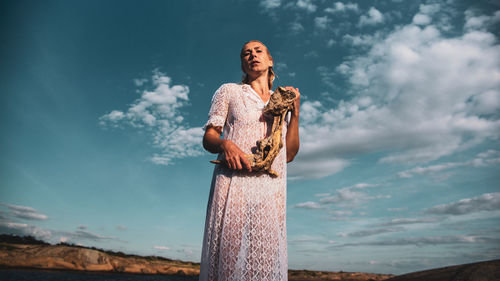 Woman standing on wooden post against sky