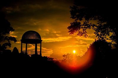 Silhouette trees against dramatic sky during sunset