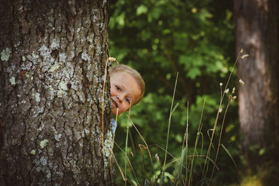 Portrait of a smiling boy behind tree