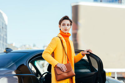 Portrait of young woman standing in car