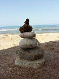 Close-up of stacked pebbles at beach against clear sky