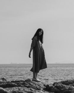 Woman standing at beach against sky