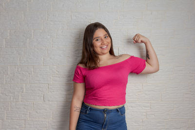 Young woman standing against wall