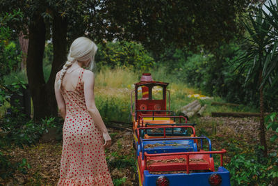 Rear view of young woman standing by miniature train at park