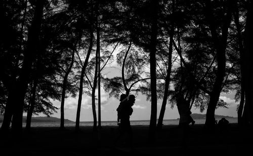 Silhouette man standing by tree on field