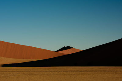 Scenic view of desert against clear blue sky