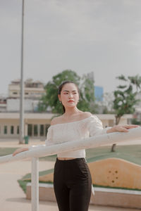 Young woman looking away while standing by railing