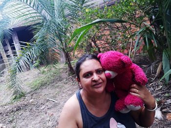 Portrait of smiling woman with teddy bear outdoors