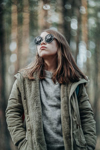 Young woman in sunglasses wearing jacket standing in winter
