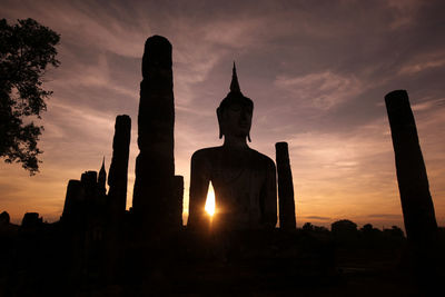 Ancient buddha statue in sukhothai historical park at sunset