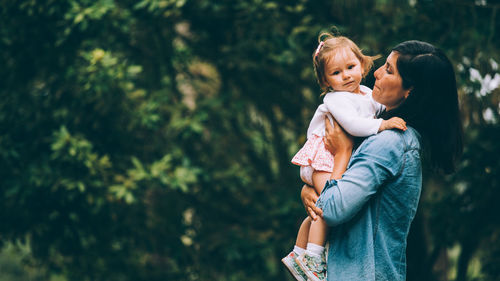 Rear view of mother holding baby at park