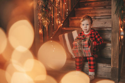 Portrait of cute girl standing against illuminated christmas tree
