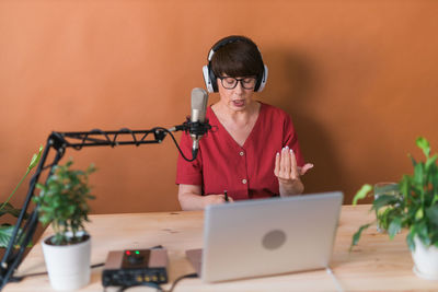 Young woman using mobile phone while sitting on table