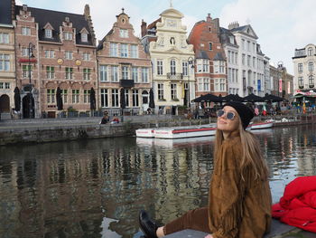 Woman in canal against buildings in city