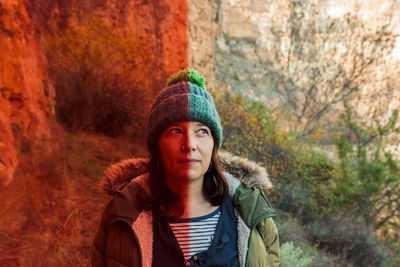 Contemplative woman in warm clothing with reflection of red plastic on face