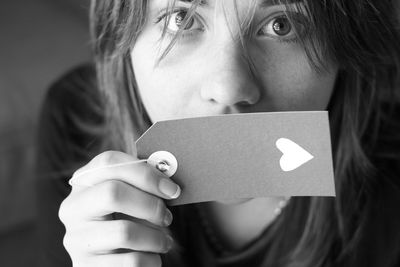 Close-up portrait of young woman covering mouth with label at home