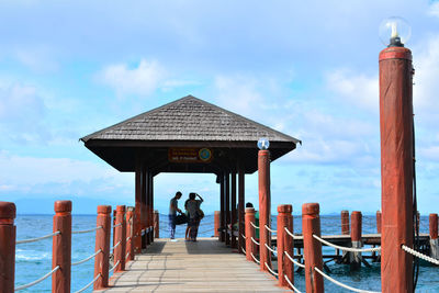 People at observation point by sea against sky