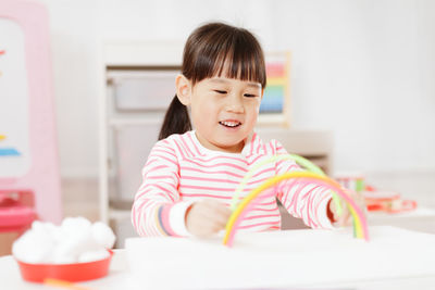 Young girl making rainbow craft using pipe cleaner at home