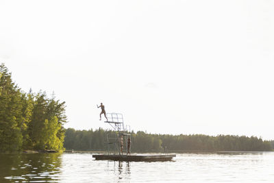 Person jumping into lake from diving tower