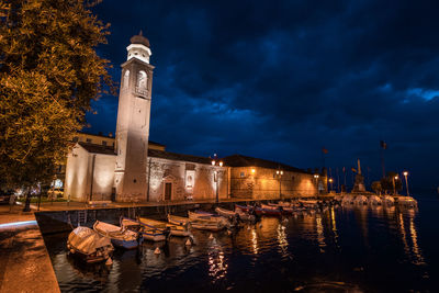 Illuminated buildings by canal against sky at night