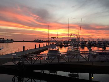 Boats moored at harbor during sunset