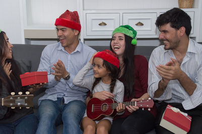 Cheerful friends sitting on sofa at home