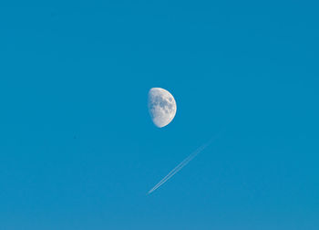 Low angle view of moon against blue sky