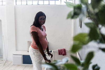 Smiling pregnant woman standing by crib at home