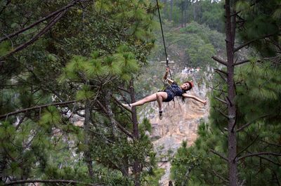 Young woman hanging on rope in forest