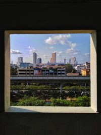 Buildings against sky seen through glass window