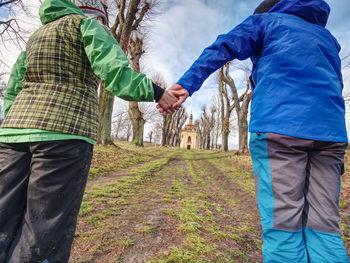 Walk together. low angle close-up of tourists holding hands and walk up to hill