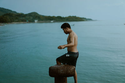 Rear view of shirtless man standing in sea