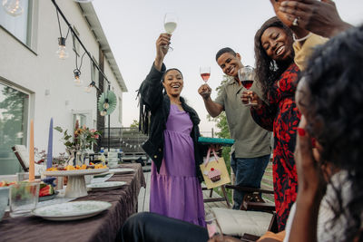 Happy male and female friends toasting drinks in back yard